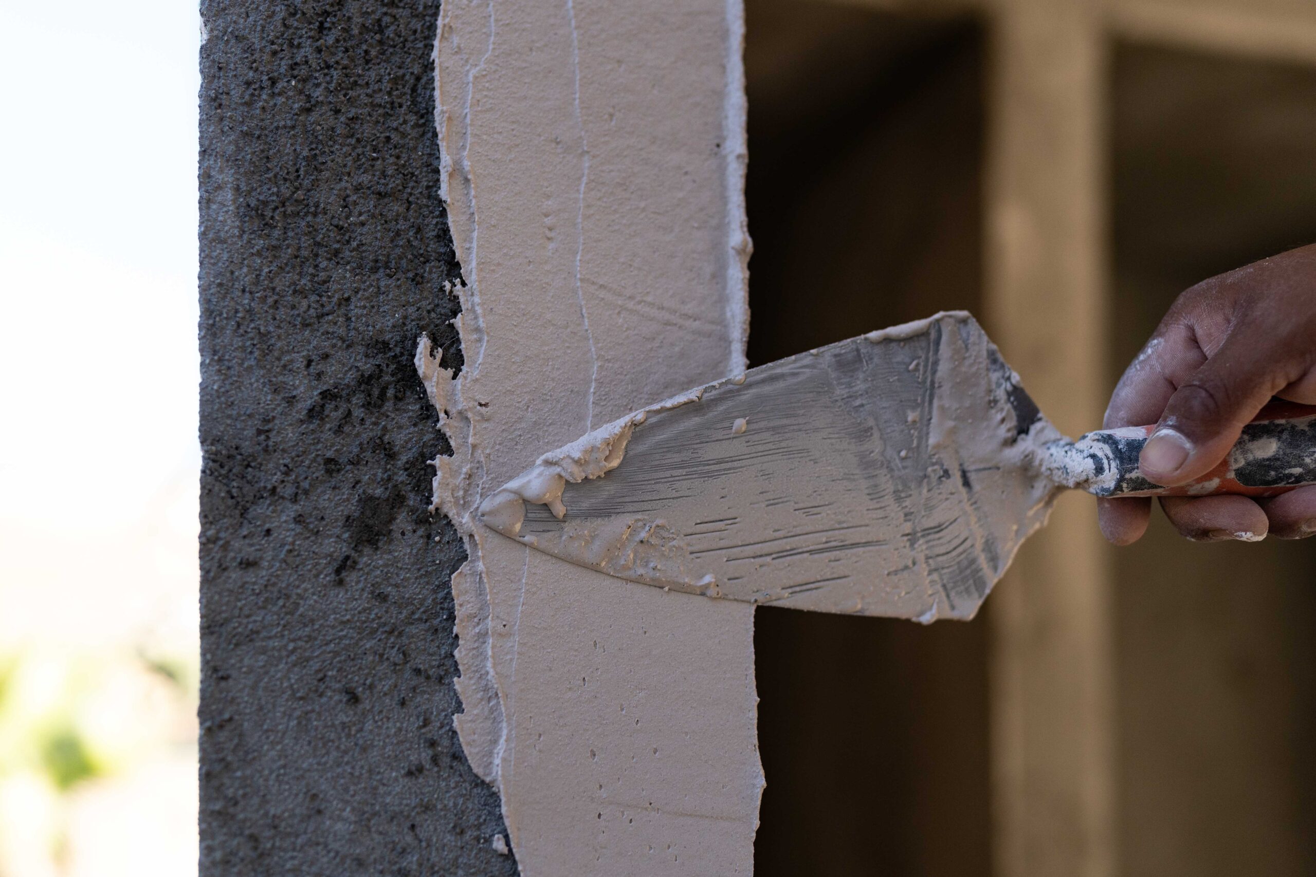Craftsman smoothing concrete column under natural light during custom home construction in Baja California Sur